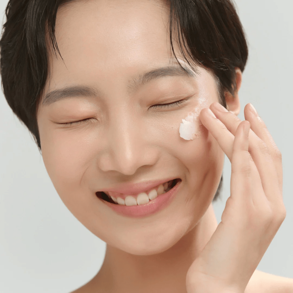 Modell mit strahlender Haut trägt Beauty of Joseon Radiance Cleansing Balm auf – koreanischer Reinigungsbalsam, der Make-up und Unreinheiten wegschmilzt.