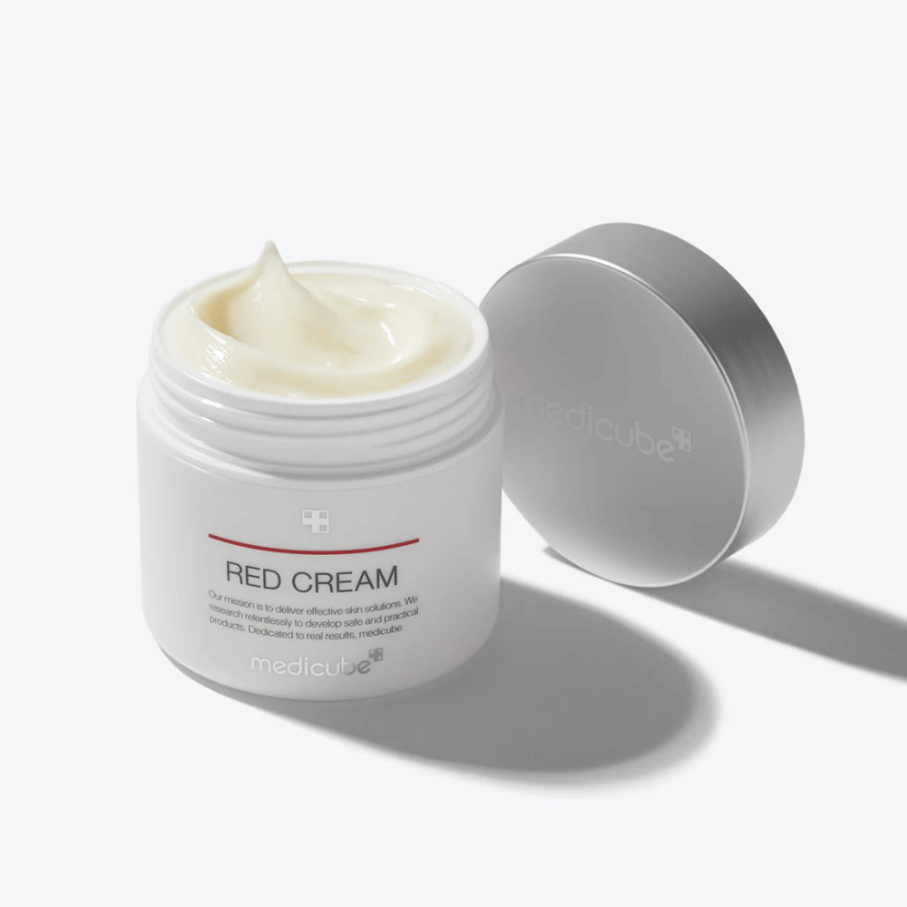 Offener Behälter mit medicube Red Cream 50ml – eine hellgelbe Gesichtscreme in weißer Verpackung mit silbernem Deckel, entwickelt für zu Akne neigende Haut.
