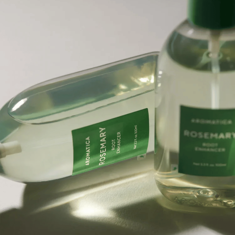 Zwei AROMATICA Rosemary Root Enhancer-Flaschen mit transparenter Schutzkappe und grünem Etikett. Nahaufnahme, die das Premiumdesign des Produkts und das natürliche Haarpflegekonzept hervorhebt.