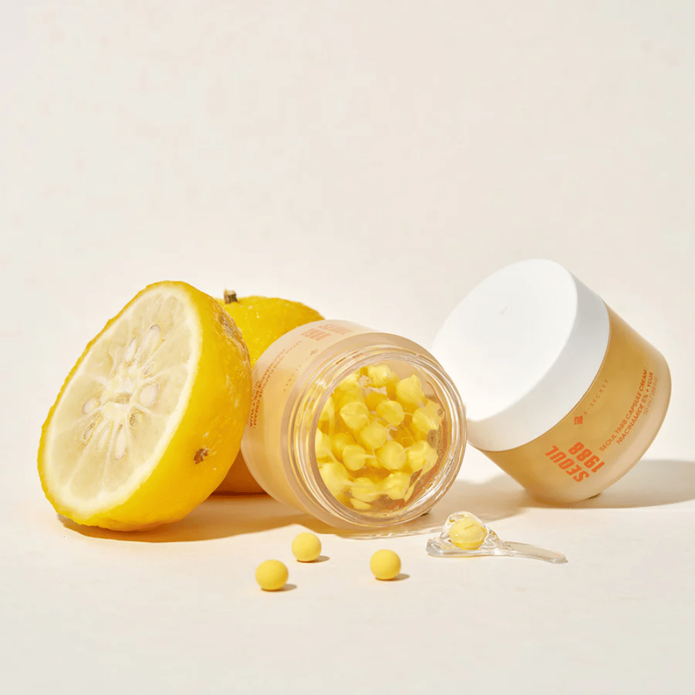 Offene Dose mit gelben Kapseln neben halbierter Yuja-Frucht, die die vitamin-C-reiche Formel hervorhebt.