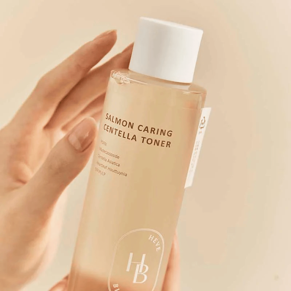 Nahaufnahme von Salmon Caring Centella Toner in der Hand – beruhigender Toner mit PDRN und Pflanzenextrakten, die helfen, die Haut zu stärken und das Gefühl von Reizungen zu reduzieren.
