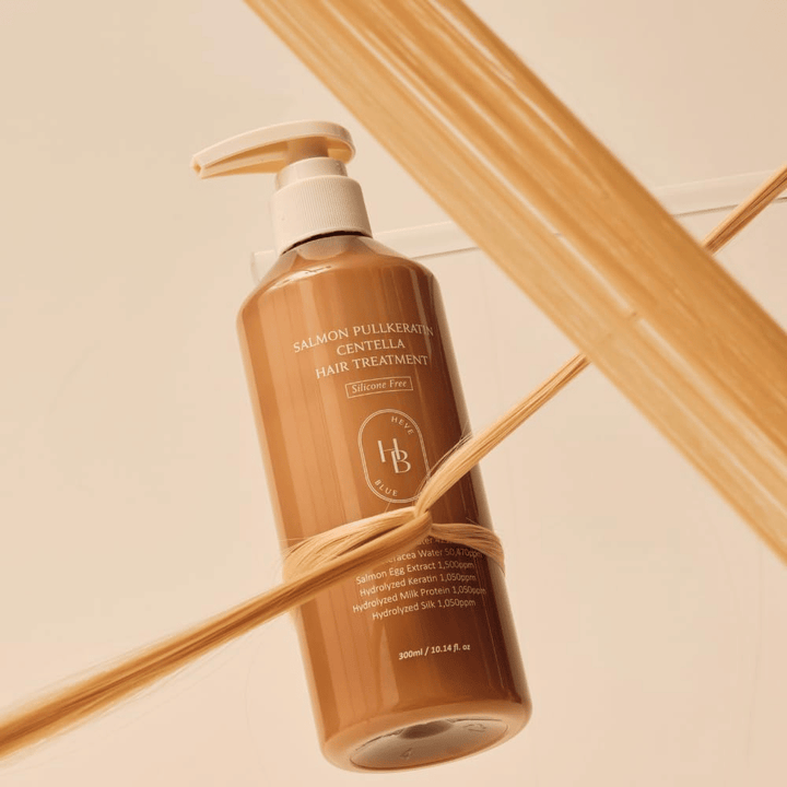 Heveblue Salmon Pullkeratin Centella Hair Treatment in brauner Flasche, umgeben von Haarsträhnen. Das Bild hebt die pflegenden Eigenschaften der Haarbehandlung hervor, mit Fokus auf Glanz, Stärke und seidig weiches Haar.