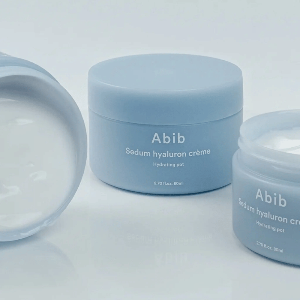 Tre burkar av Abib Sedum Hyaluron Crème Hydrating Pot 80 ml i ljusblå minimalistisk design, varav en öppen burk visar den krämiga vita konsistensen.