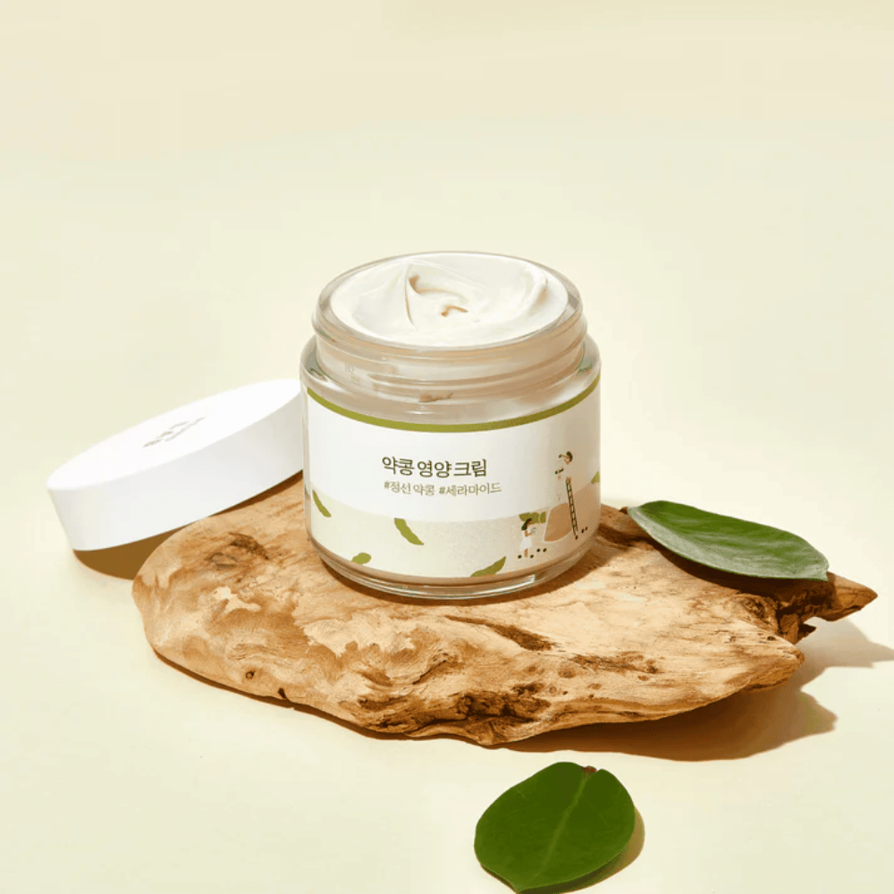 Mixsoon Soybean Nourishing Cream in einem offenen Gefäß auf einem Holzstück mit grünen Blättern. Eine nährstoffreiche Creme mit fermentierten Sojabohnen und Ceramiden.