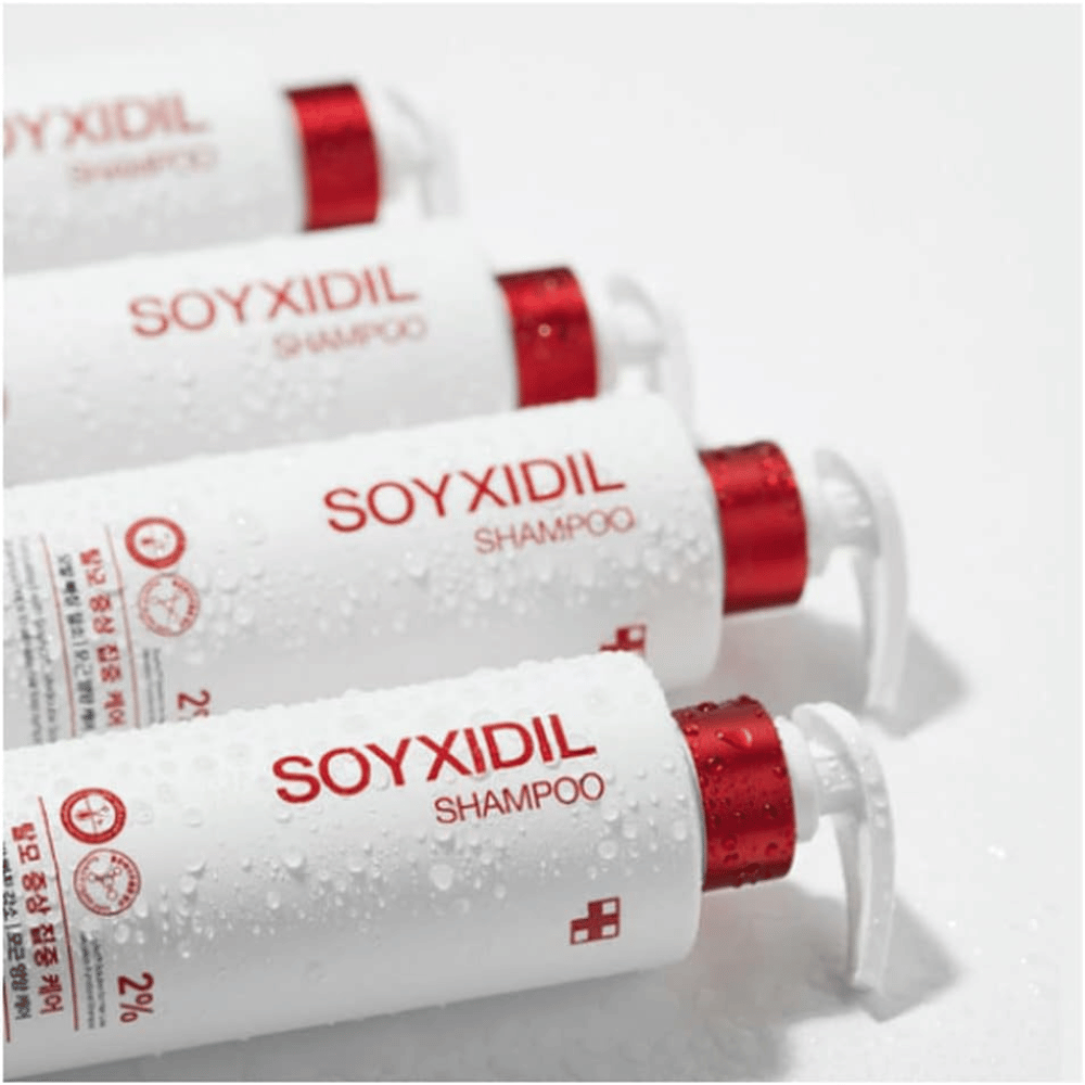 Mehrere Flaschen von Medicube Soyxidil Shampoo liegen in einer Reihe mit Wassertropfen – zeigt das frische und pflegende Gefühl des Produkts.