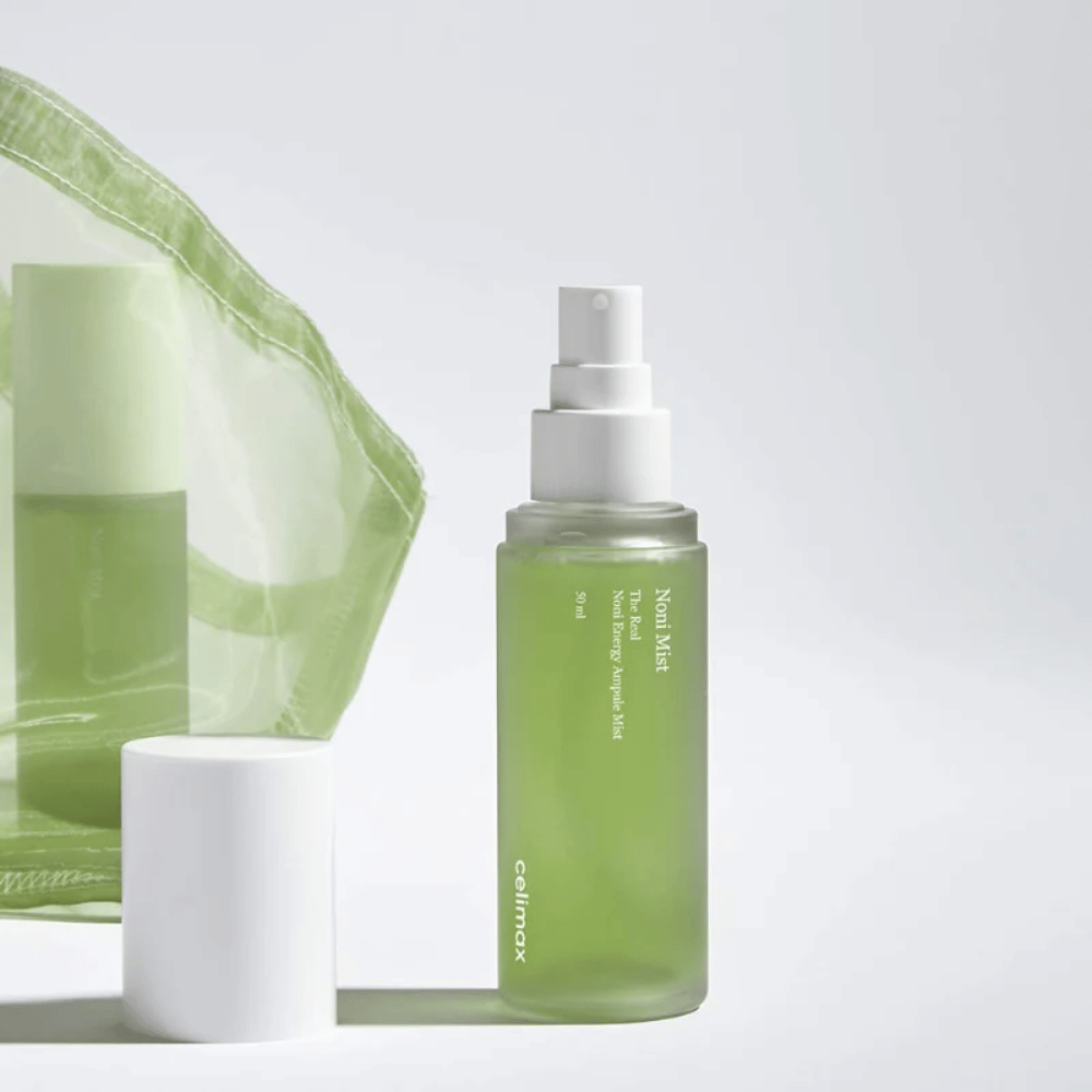 Eine Flasche mit Celimax Noni Mist, eine grüne Sprühflasche mit weißer Pumpe, die neben einem Deckel steht. Das Produkt ist in einer durchsichtigen Plastiktüte verpackt und wird als Noni Energy Ampule Mist vermarktet.