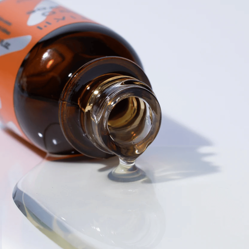 Nahaufnahme von TIA'M Vita C Source-Serum, das aus einer braunen Glasflasche fließt. Die klare Formel des Serums hebt seinen konzentrierten Vitamin-C-Gehalt für eine strahlende Haut hervor.