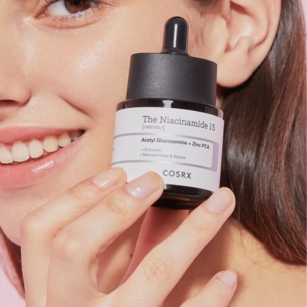 Eine Frau hält eine Flasche COSRX Niacinamide 15 Serum 20ml für Niacinamid und die Talgproduktion.