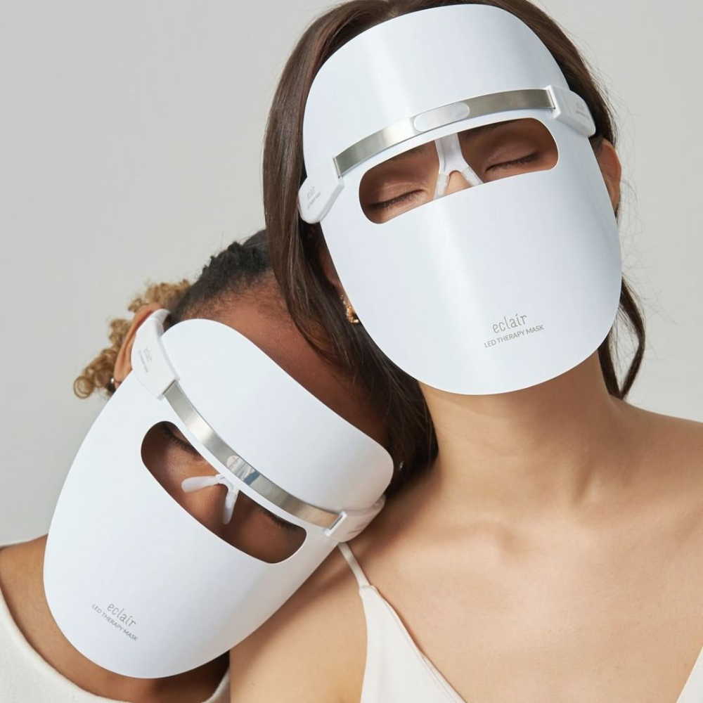 Zwei Frauen, die weiße Masken tragen, demonstrieren ECLAIR LED Therapy Mask für Hauttönungsverbesserungen.