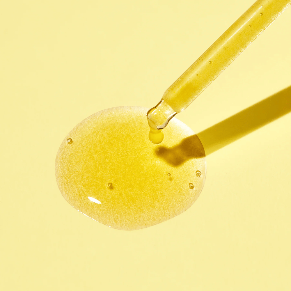 Ein Tropfen Flüssigkeit auf einem gelben Hintergrund, mit dem MISSHAs Vita C Plus Spot Correcting & Firming Ampoule.