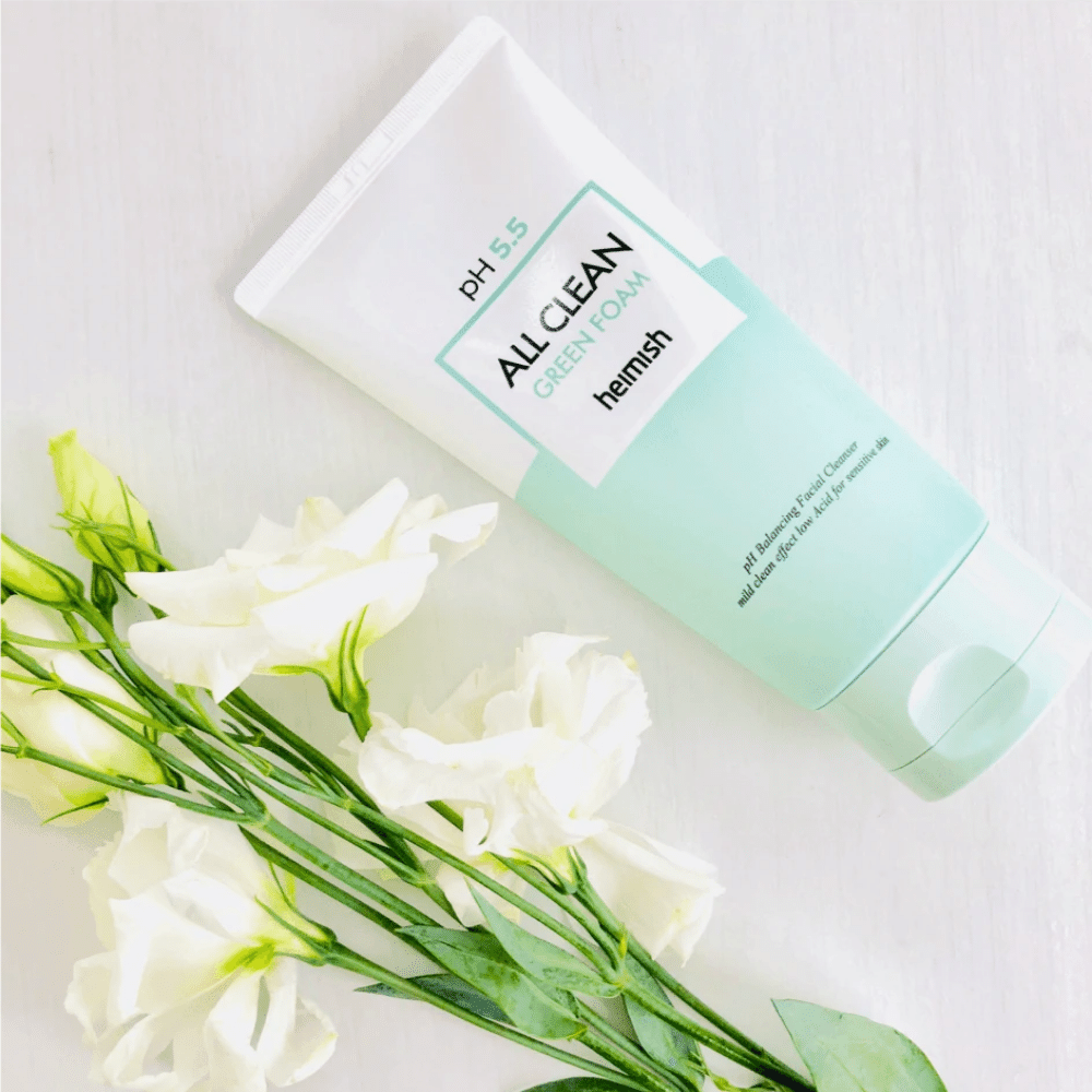 Eine Tube heimish All Clean Green Foam 150ml neben weißen Blumen.